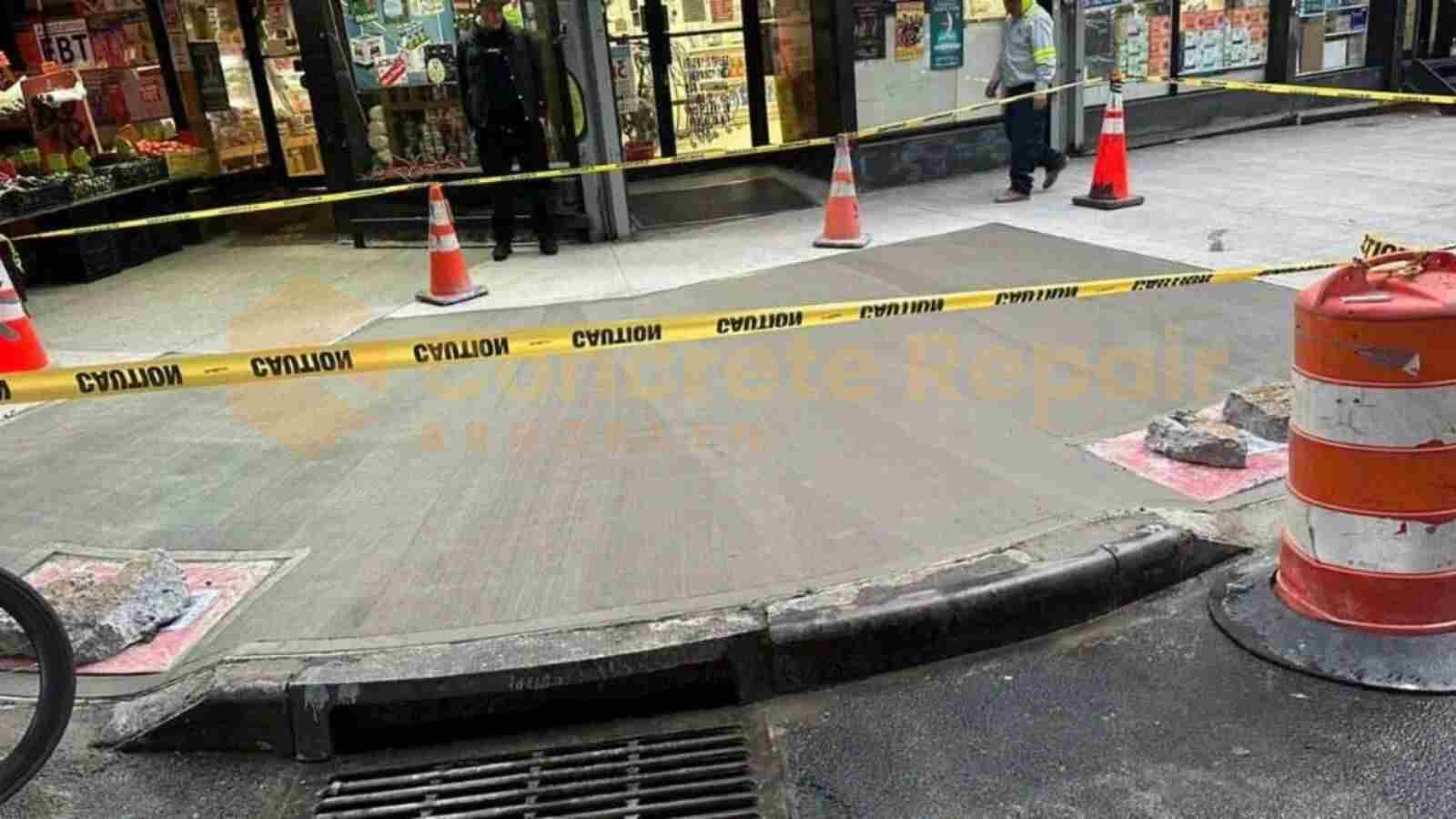 A man is on a sidewalk near a construction site, observing the ongoing concrete resurfacing project.