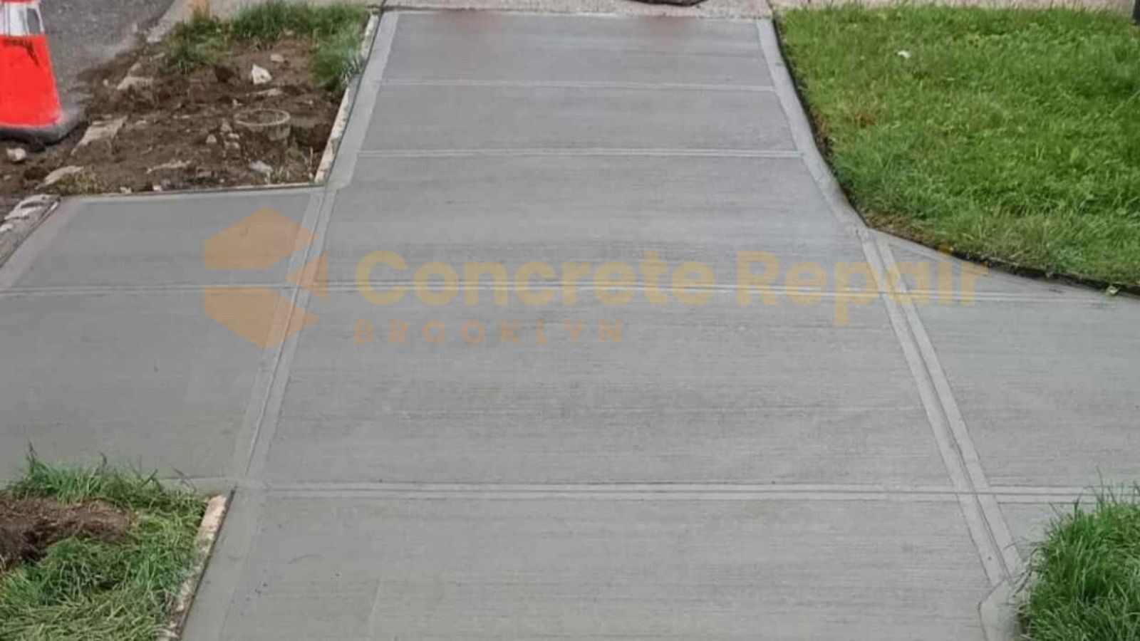 Concrete Sidewalk sloped for drainage, leading to a house, surrounded by grass and landscaping.
